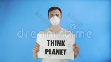 年轻的激进分子，脸上戴着面具，蓝色背景上贴着《思考星球》海报